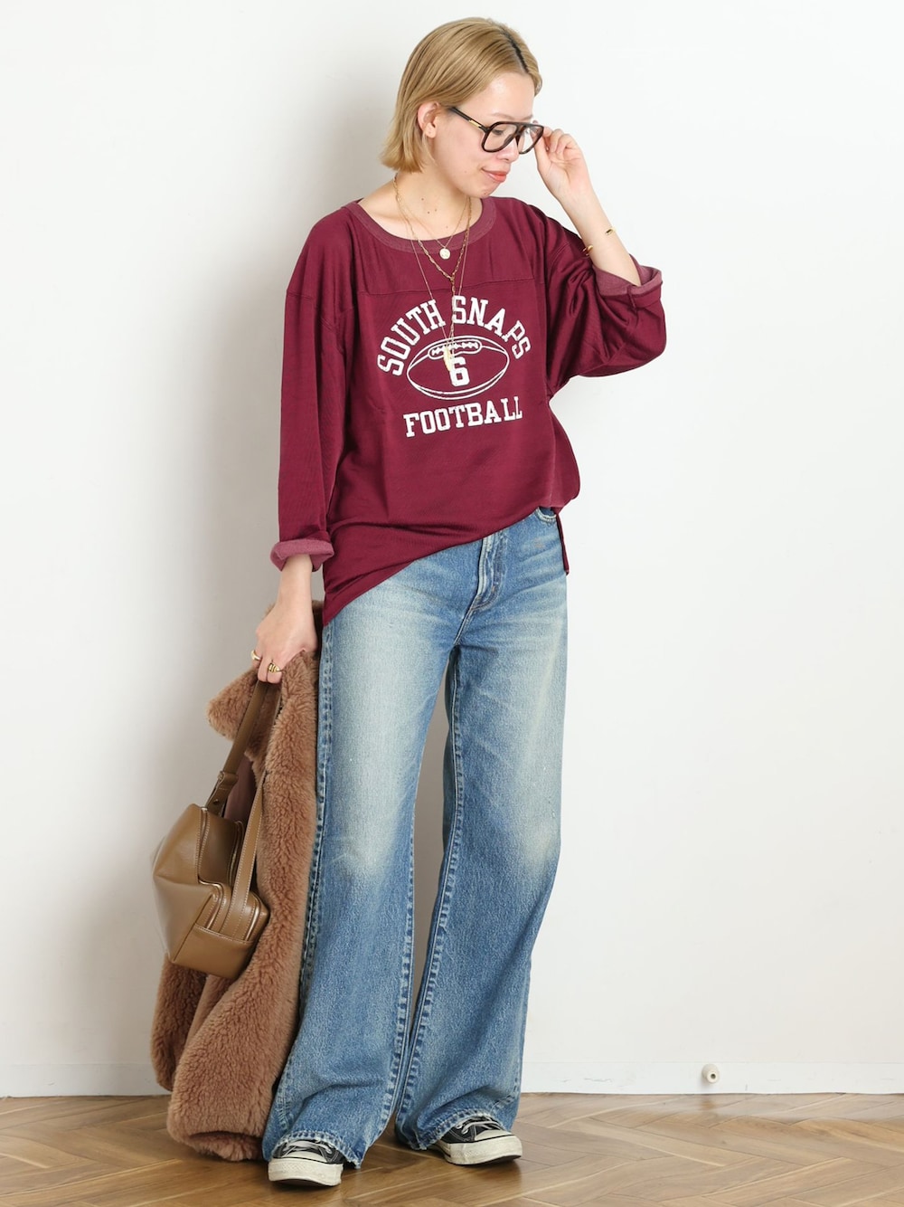 ブルー系のデニムパンツ、レッド系のTシャツ/カットソー、ゴールド系のブレスレットを着用したレディースの秋コーディネートの1枚目の写真