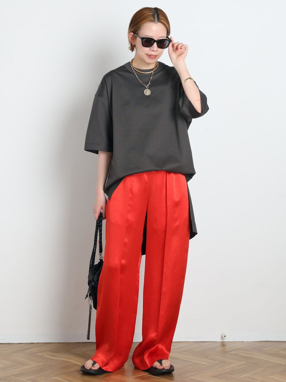 レッド系のその他パンツ、グレー系のTシャツ/カットソー、ブラック系のショルダーバッグを着用したレディースの春コーディネートの1枚目の写真
