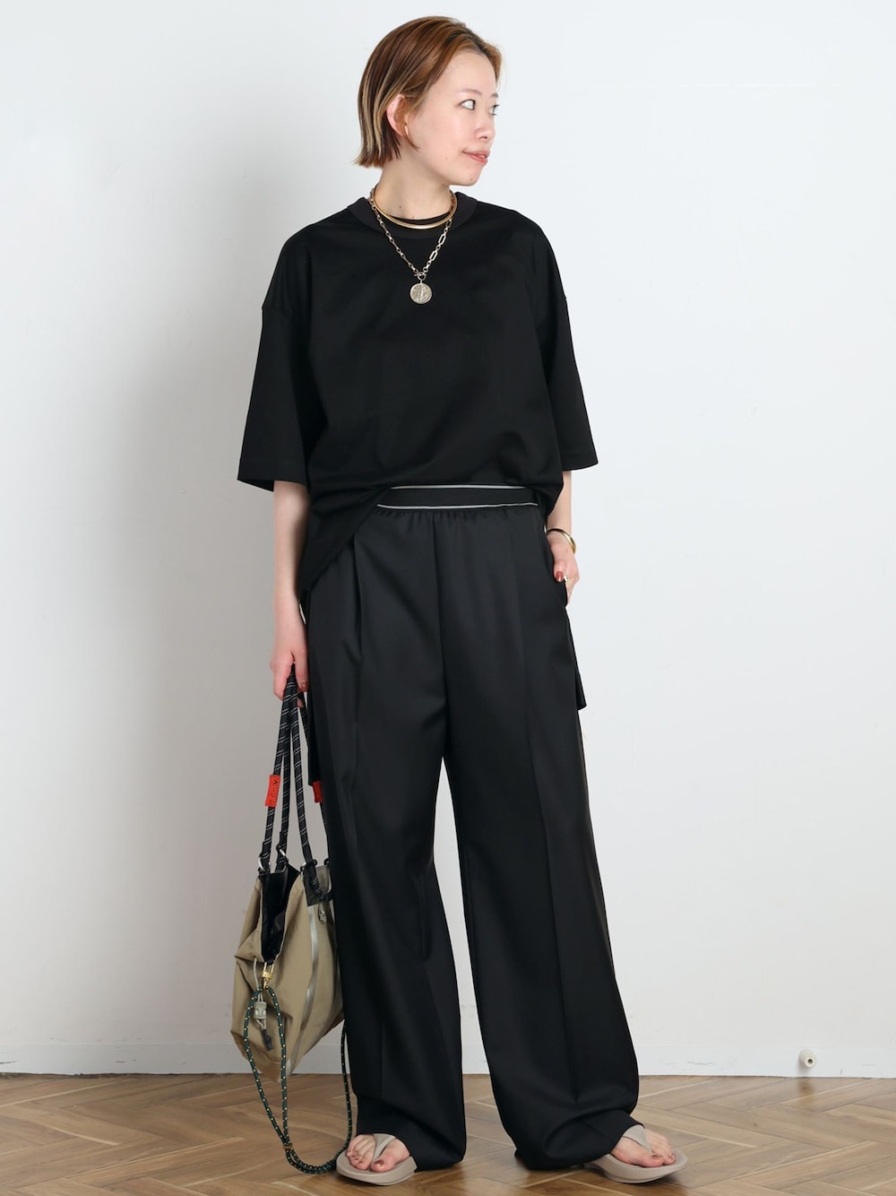 ブラック系のスラックス、ブラック系のTシャツ/カットソー、ベージュ系のサンダルを着用したレディースの春コーディネートの1枚目の写真