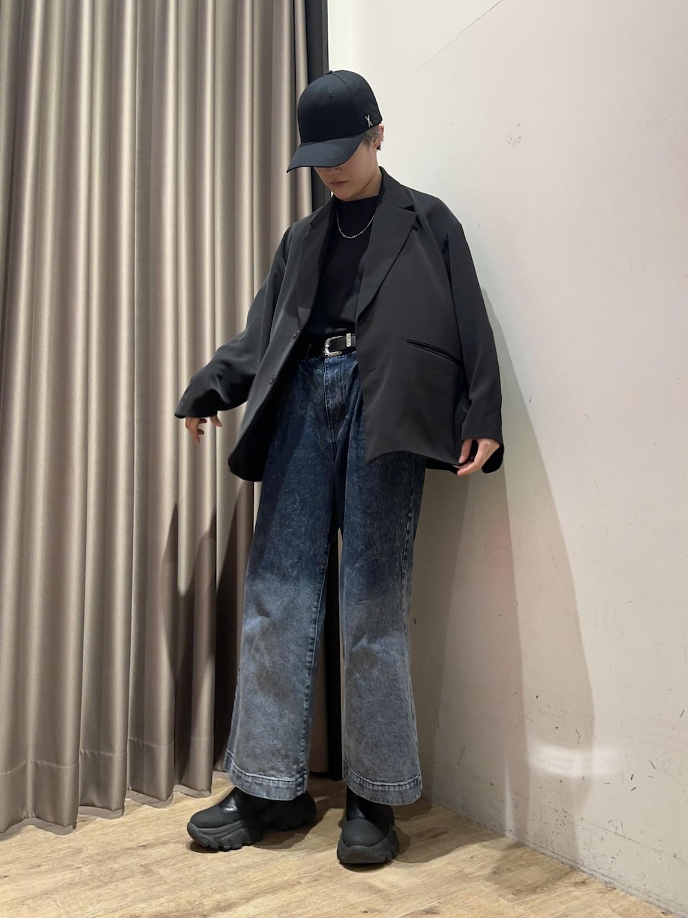 ブルー系のデニムパンツ、ブラック系のテーラードジャケット、ブラック系のキャップを着用したメンズの春コーディネートの1枚目の写真