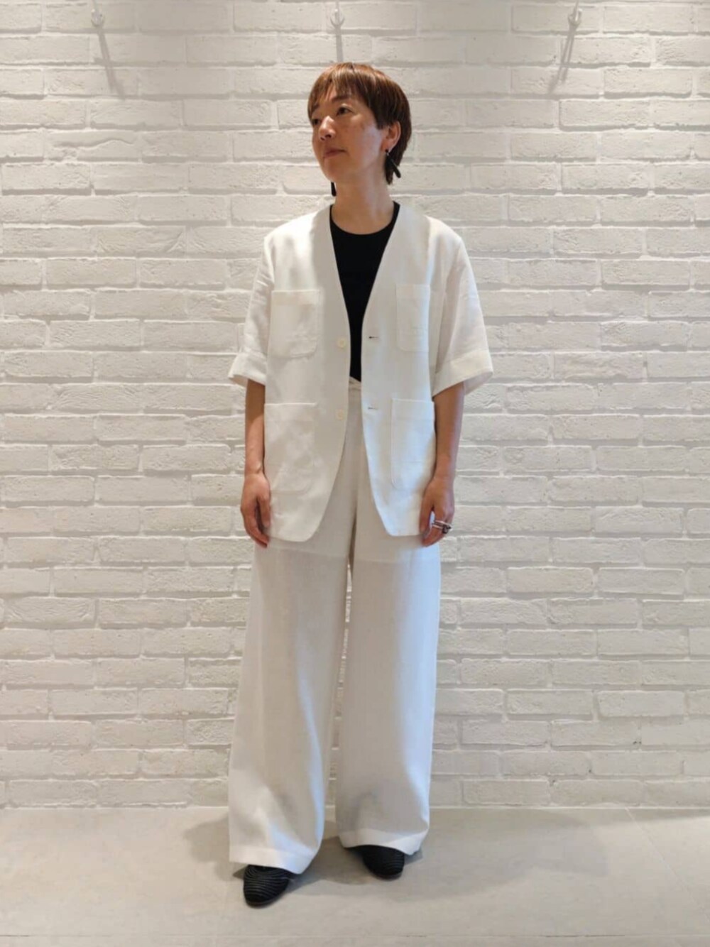 ホワイト系のノーカラージャケット、ブルー系のタンクトップ、ホワイト系のその他パンツを着用したレディースの夏コーディネートの1枚目の写真