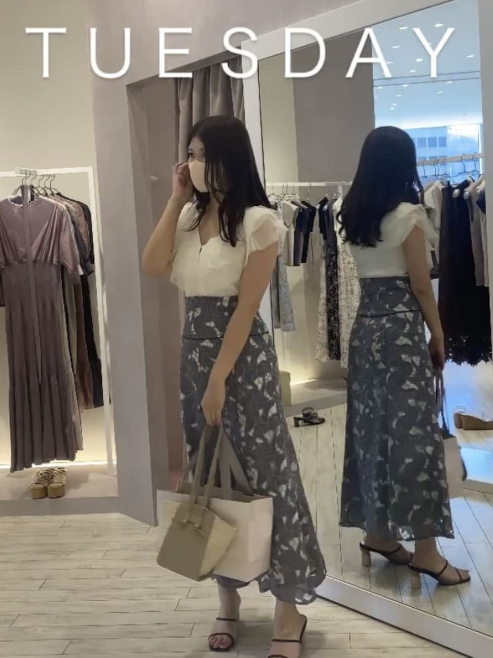 ベージュ系のトートバッグ、ホワイト系のカーディガン/ボレロ、ブルー系のスカートを着用したレディースの夏コーディネートの1枚目の写真