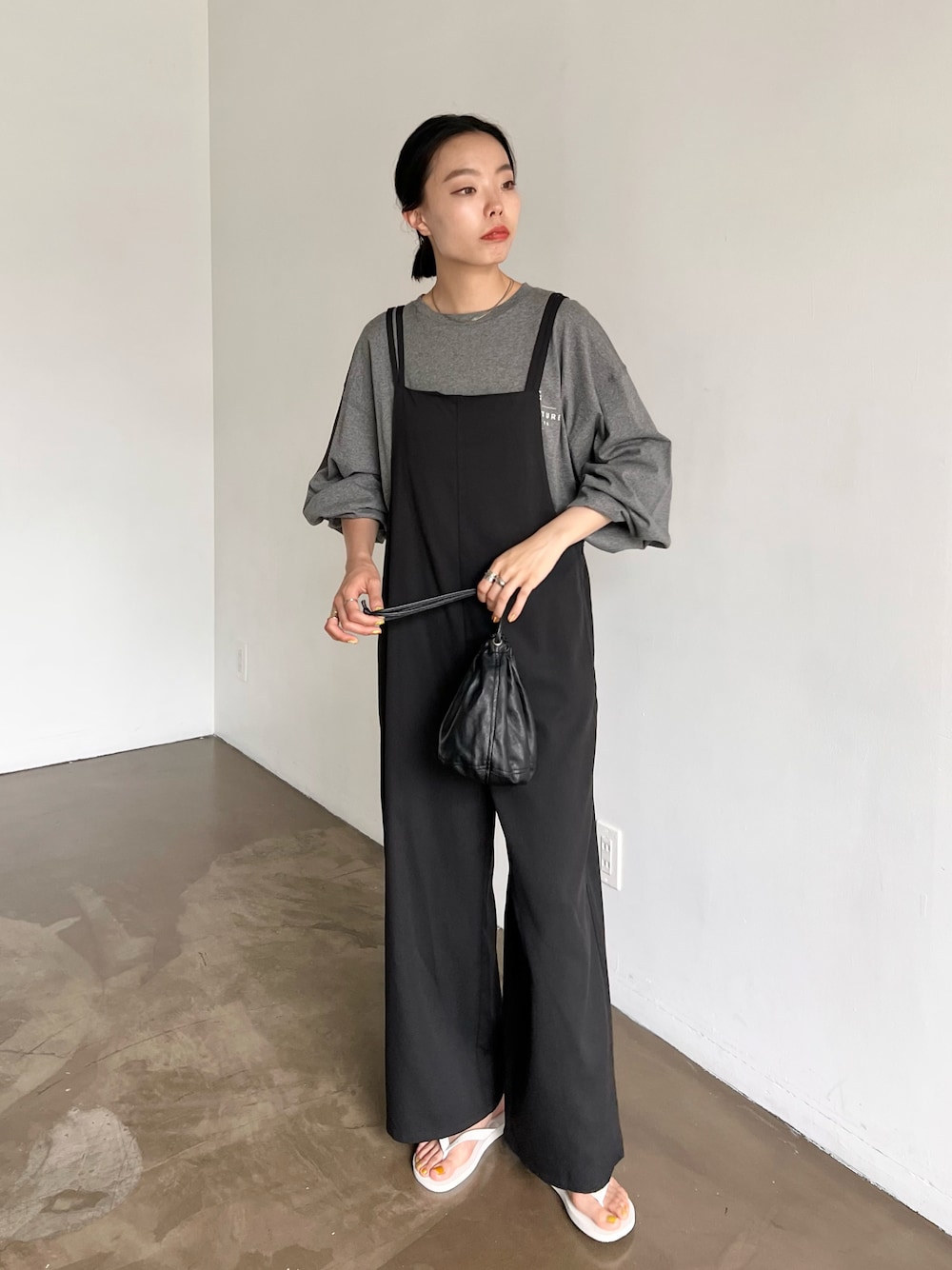 ブラック系のサロペット/オーバーオール、ブラック系のハンドバッグ、グレー系のTシャツ/カットソーを着用したレディースの夏コーディネートの1枚目の写真