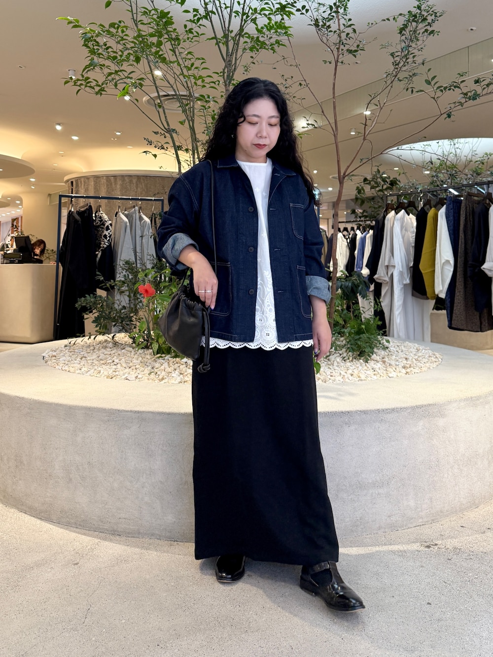 ブルー系のカバーオール、ブラック系のショルダーバッグ、ブラック系のスカートを着用したレディースの秋コーディネートの1枚目の写真