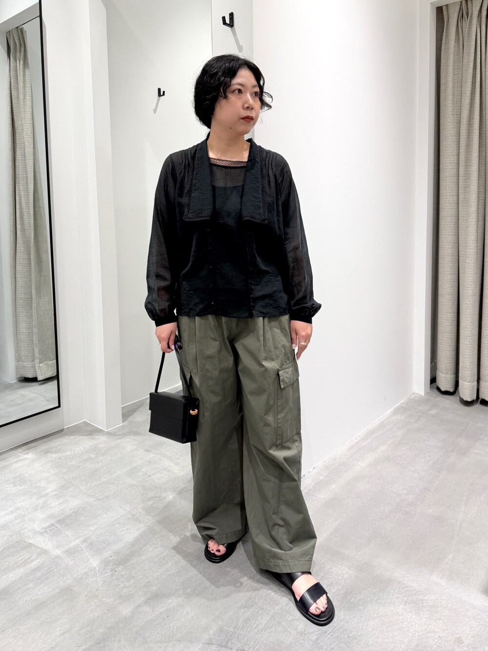 ブラック系のサンダル、ブラック系のシャツ/ブラウス、ブラック系のバッグを着用したレディースの春コーディネートの1枚目の写真