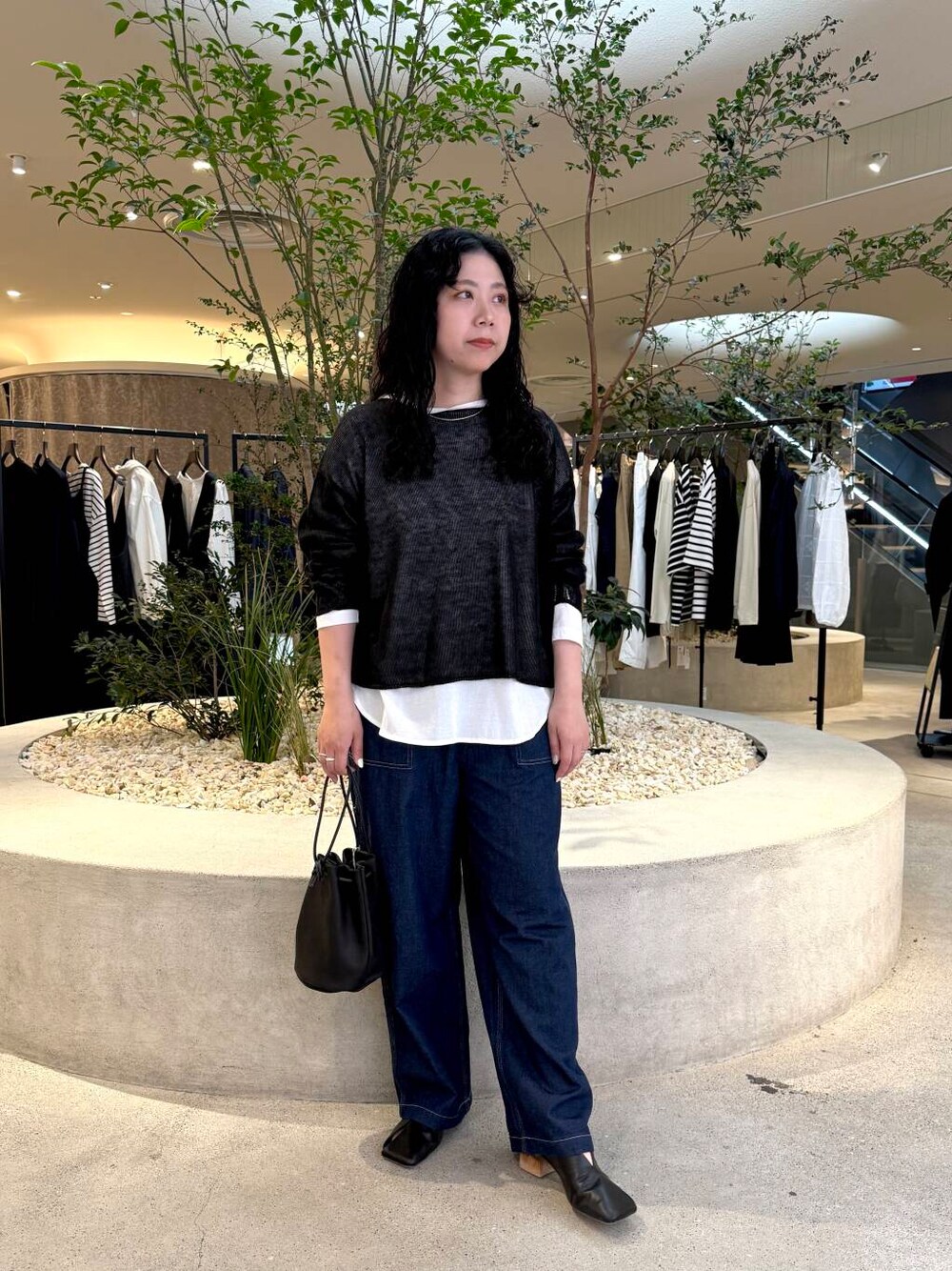 ホワイト系のTシャツ/カットソー、ブルー系のデニムパンツ、ブラック系のニット/セーターを着用したレディースの春コーディネートの1枚目の写真