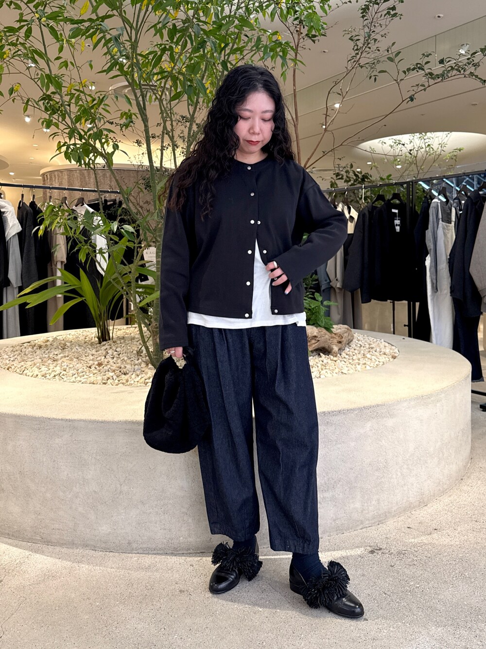 ブラック系のショルダーバッグ、ブラック系のドレスシューズ、ブルー系のデニムパンツを着用したレディースの冬コーディネートの1枚目の写真