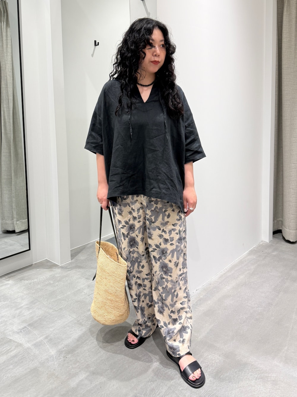 グレー系のその他パンツ、ベージュ系のかごバッグ、ブラック系のサンダルを着用したレディースの春コーディネートの1枚目の写真