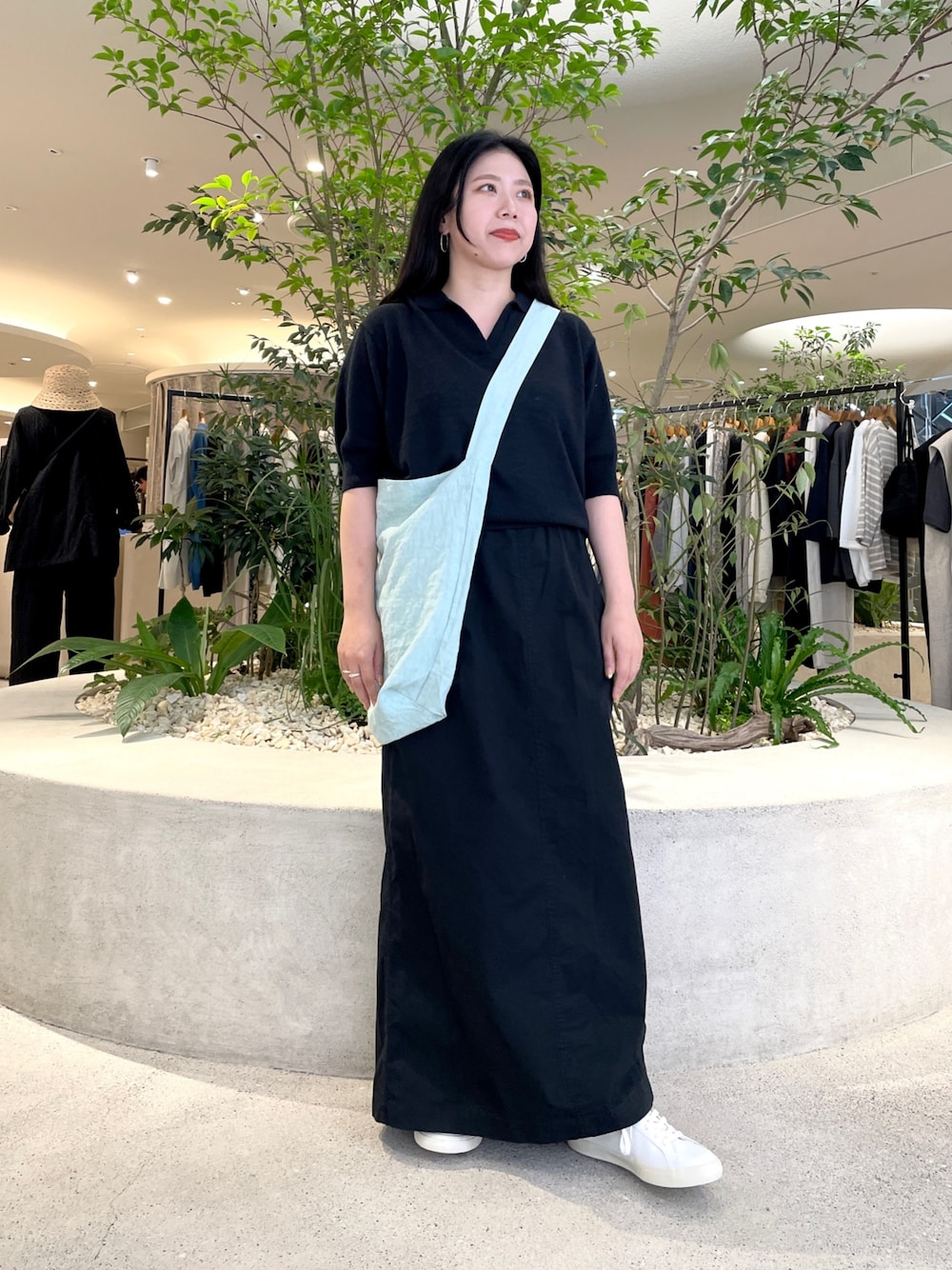 グリーン系のショルダーバッグ、ブラック系のニット/セーター、ブラック系のスカートを着用したレディースの夏コーディネートの1枚目の写真