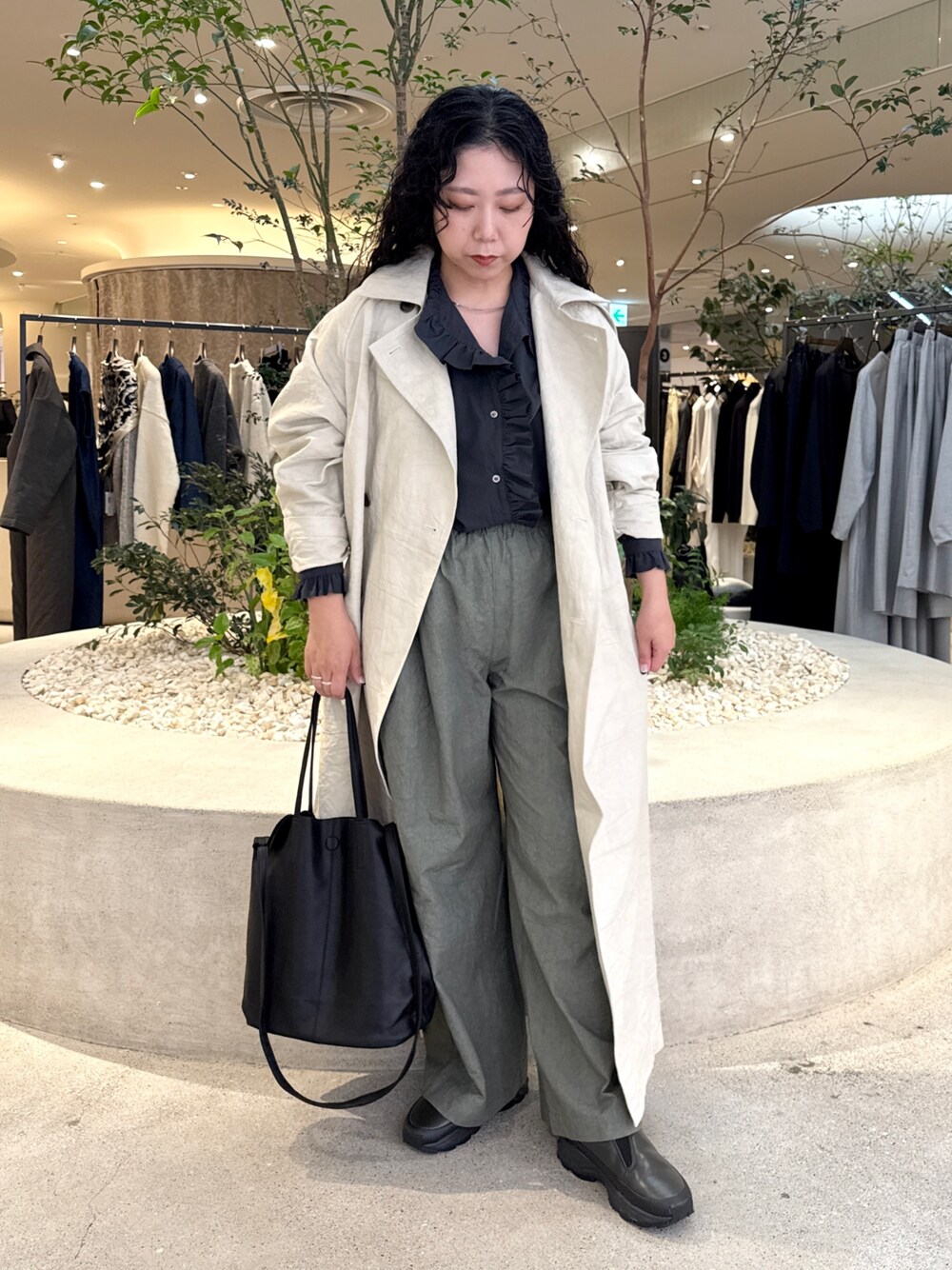 ブラック系のトートバッグ、グリーン系のその他パンツ、ベージュ系のトレンチコートを着用したレディースの秋コーディネートの1枚目の写真