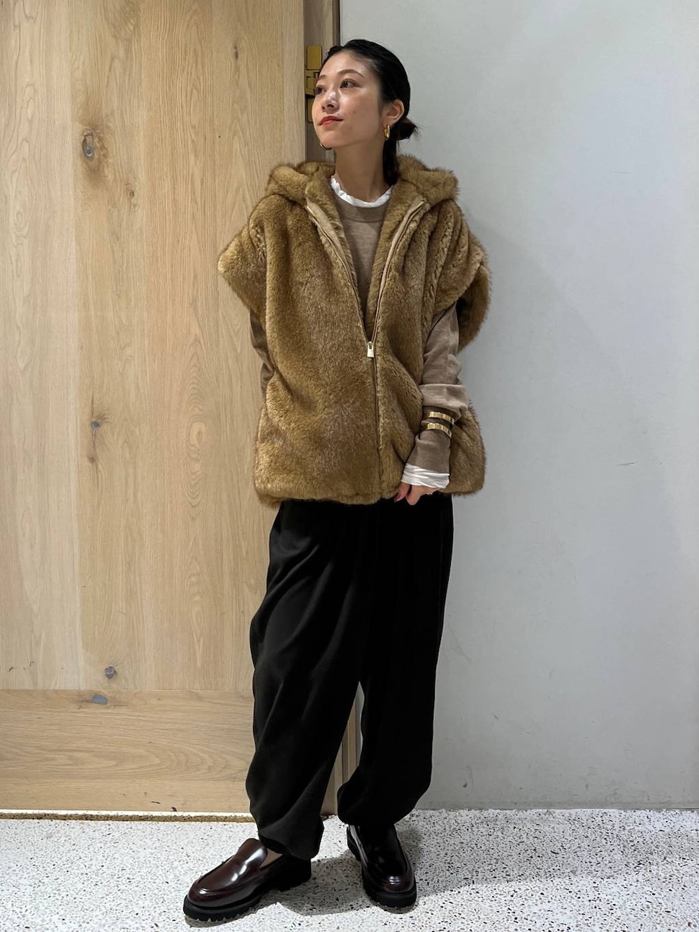 ホワイト系のTシャツ/カットソー、ベージュ系のベスト、ブラウン系のニット/セーターを着用したレディースの秋コーディネートの1枚目の写真