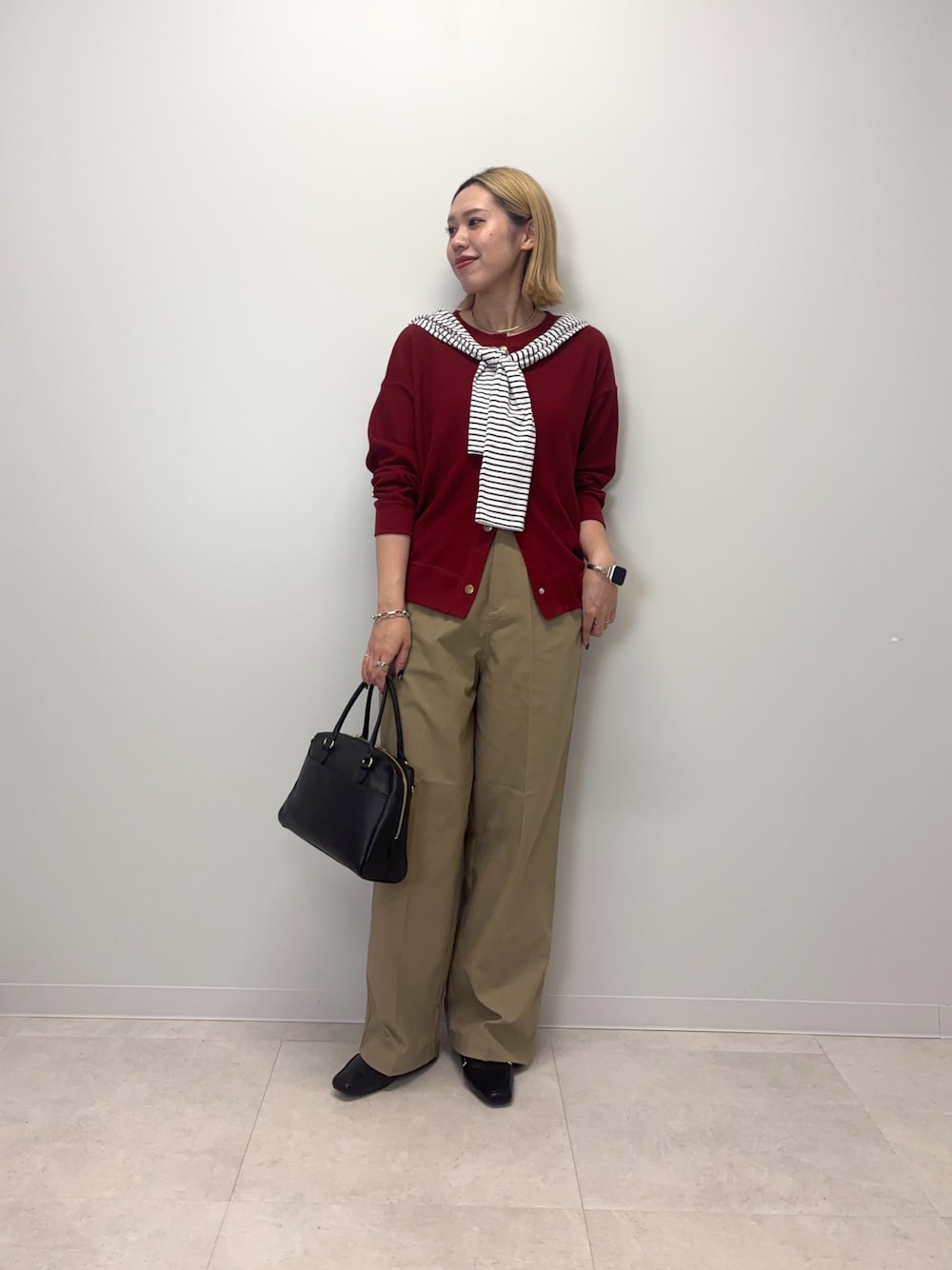 レッド系のカーディガン/ボレロ、ベージュ系のその他パンツ、ブラック系のボストンバッグを着用したレディースの秋コーディネートの1枚目の写真