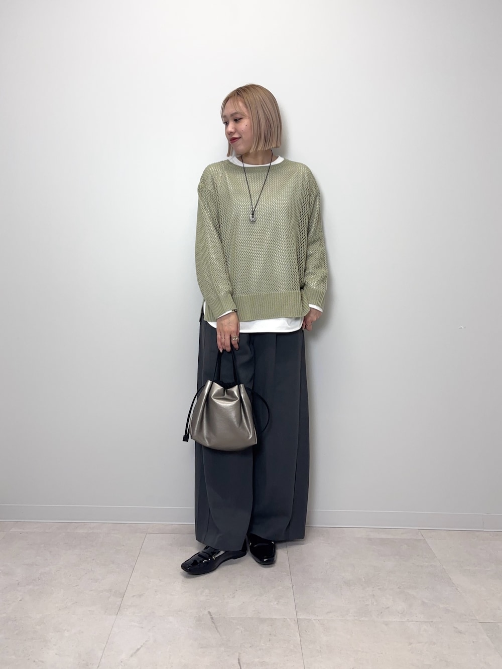 グリーン系のニット/セーター、グレー系のその他パンツ、シルバー系のショルダーバッグを着用したレディースの春コーディネートの1枚目の写真
