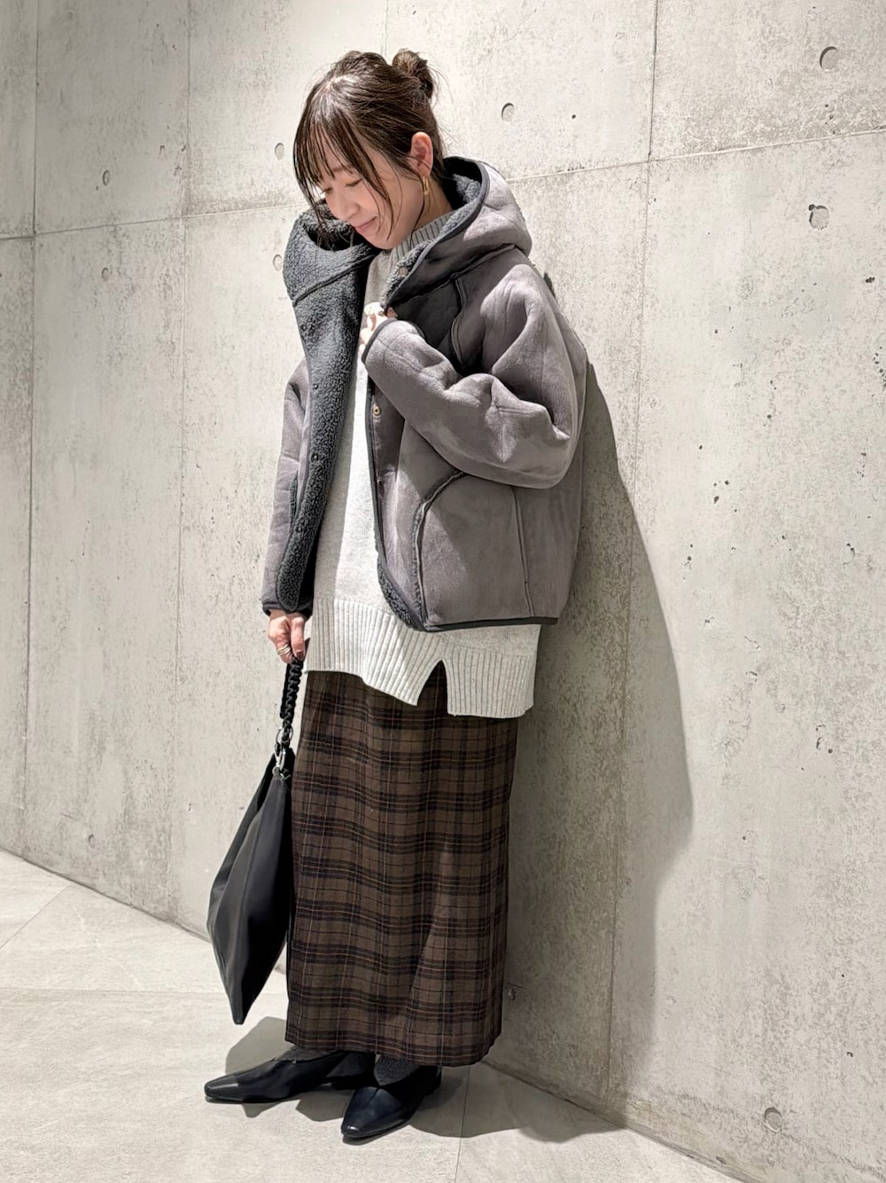 ブラック系のムートンコート、グレー系のニット/セーター、ベージュ系のスカートを着用したレディースの秋コーディネートの1枚目の写真