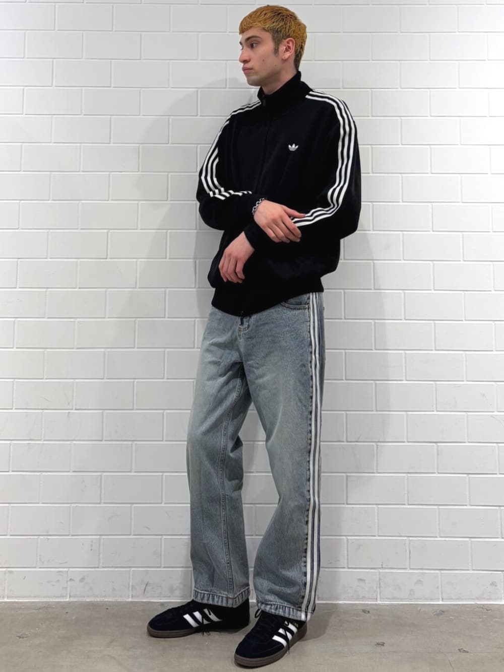 ブラック系のジャージ、ブラック系のスニーカー、ブルー系のデニムパンツを着用したメンズの春コーディネートの1枚目の写真