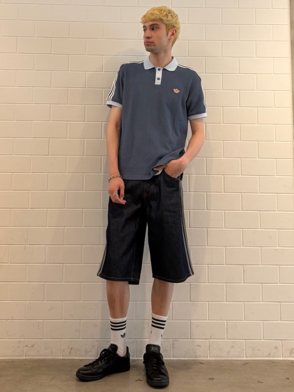 ブラック系のスニーカー、ブルー系のデニムパンツ、ブルー系のポロシャツを着用したメンズの夏コーディネートの1枚目の写真