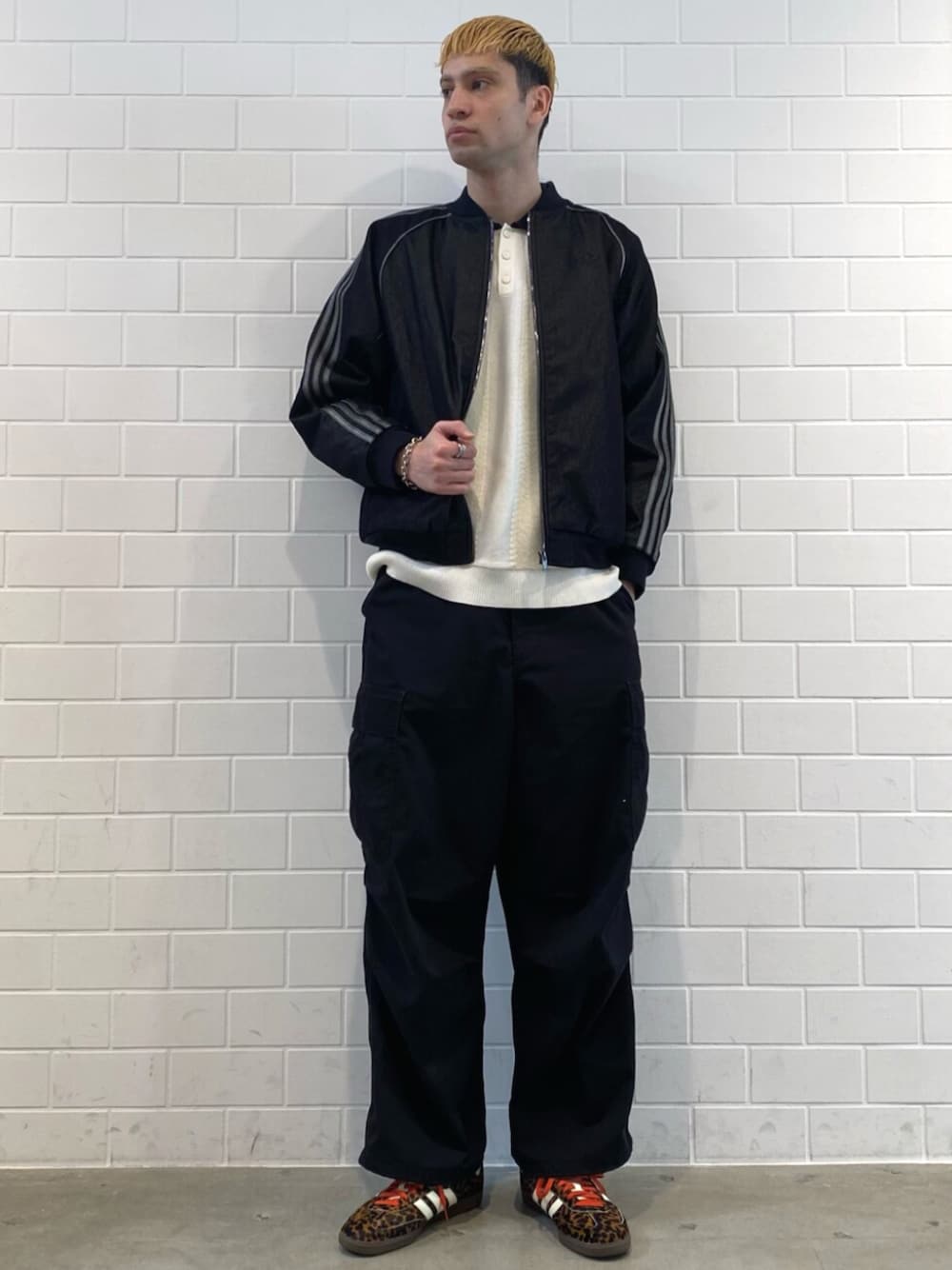 ブラック系のスニーカー、ホワイト系のニット/セーター、ブラック系のデニムジャケットを着用したメンズの秋コーディネートの1枚目の写真