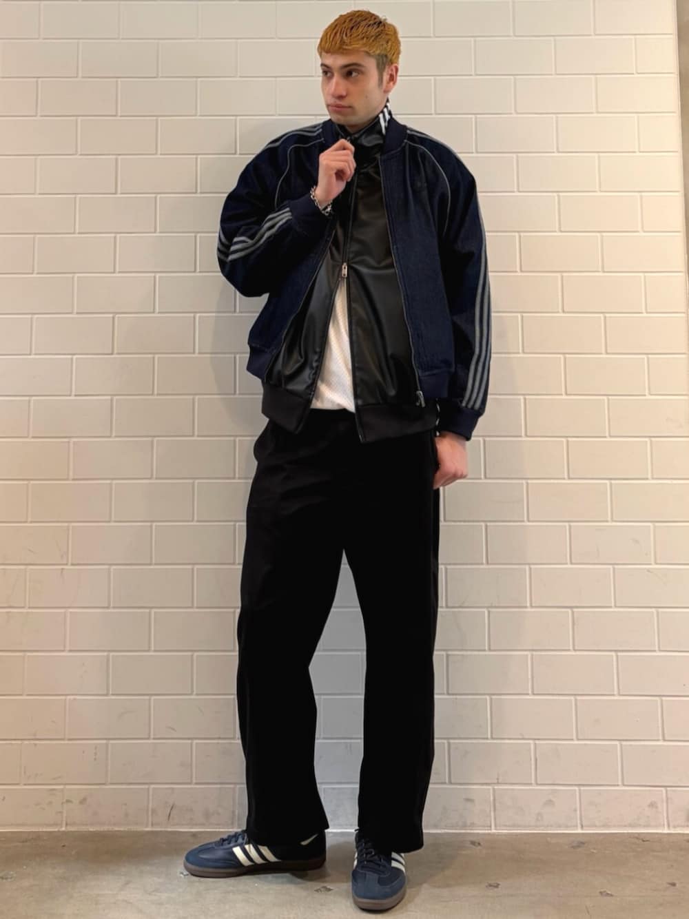 ブルー系のスニーカー、ブルー系のデニムジャケット、ブラック系のブルゾンを着用したメンズの春コーディネートの1枚目の写真