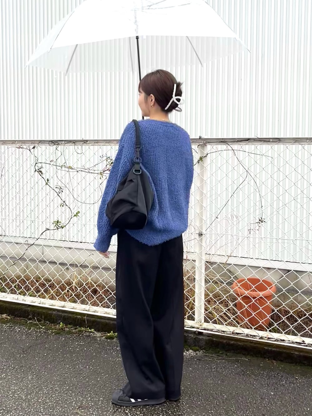 ブルー系のニット/セーター、ブラック系のショルダーバッグ、ブラック系のスラックスを着用したレディースの冬コーディネートの1枚目の写真