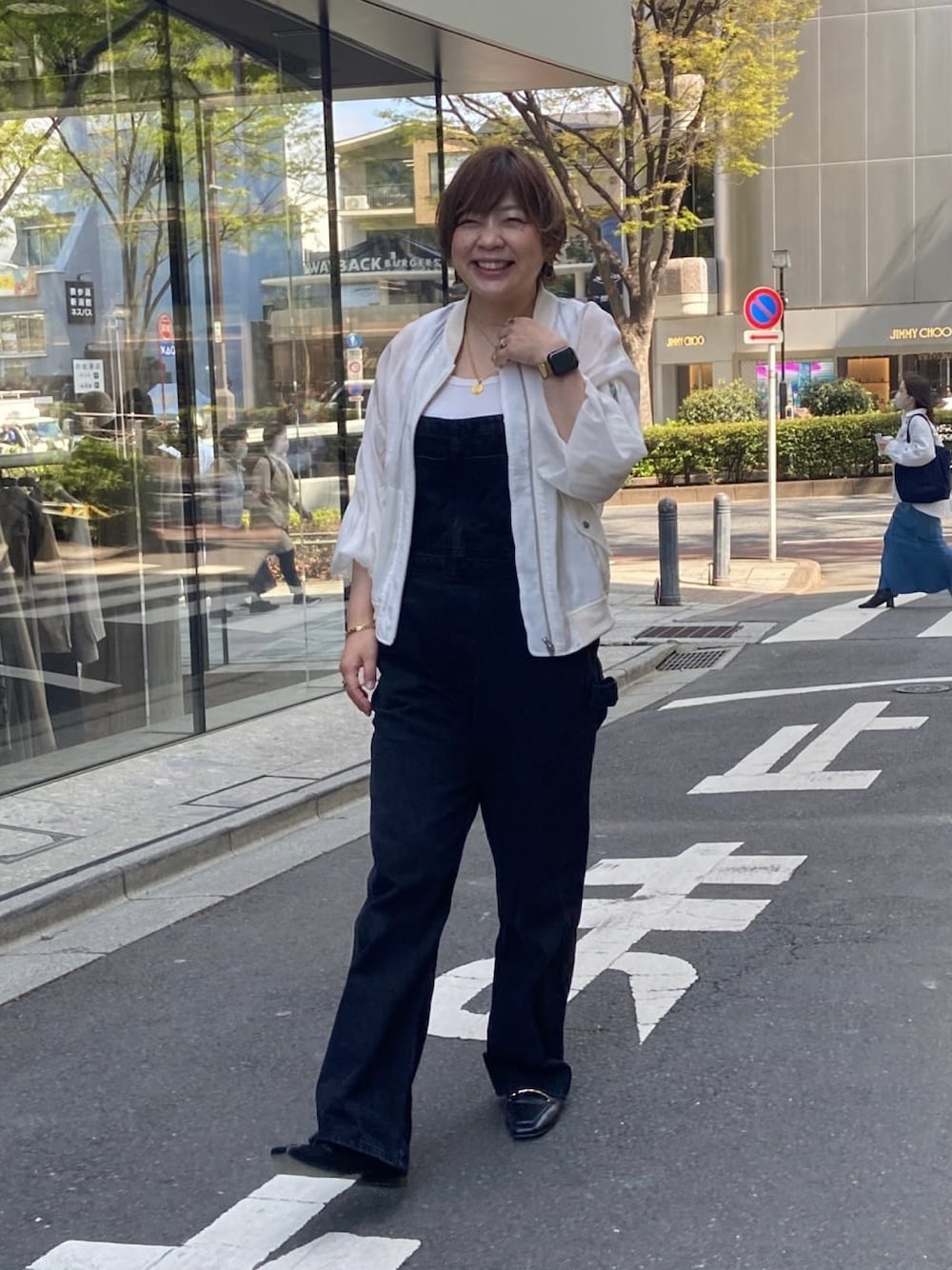 ホワイト系のミリタリージャケット、ブラック系のサロペット/オーバーオール、ホワイト系のタンクトップを着用したレディースの春コーディネートの1枚目の写真