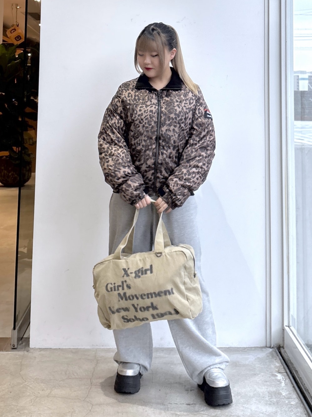 ベージュ系のナイロンジャケット、グレー系のスウェットパンツ、ベージュ系のトートバッグを着用したレディースの秋コーディネートの1枚目の写真