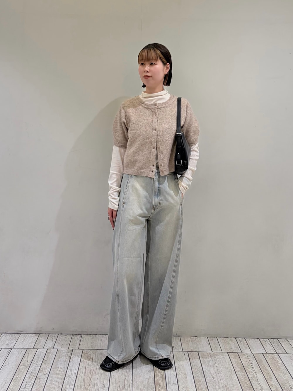 ベージュ系のカーディガン/ボレロ、ブルー系のデニムパンツ、ブラック系のショルダーバッグを着用したレディースの秋コーディネートの1枚目の写真