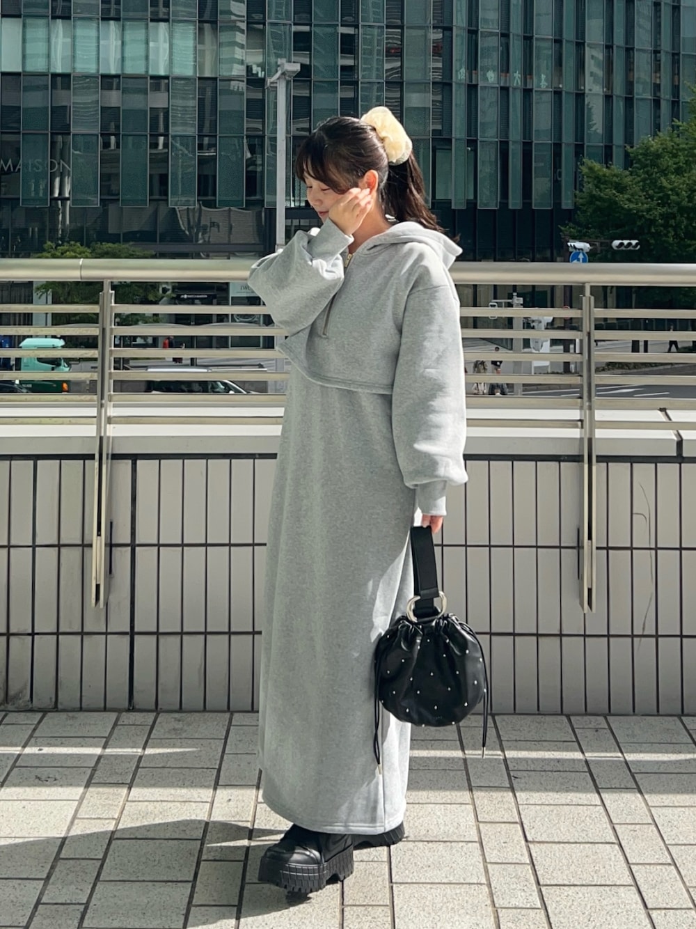 ブラック系のスニーカー、グレー系のワンピース、ブラック系のハンドバッグを着用したレディースの秋コーディネートの1枚目の写真