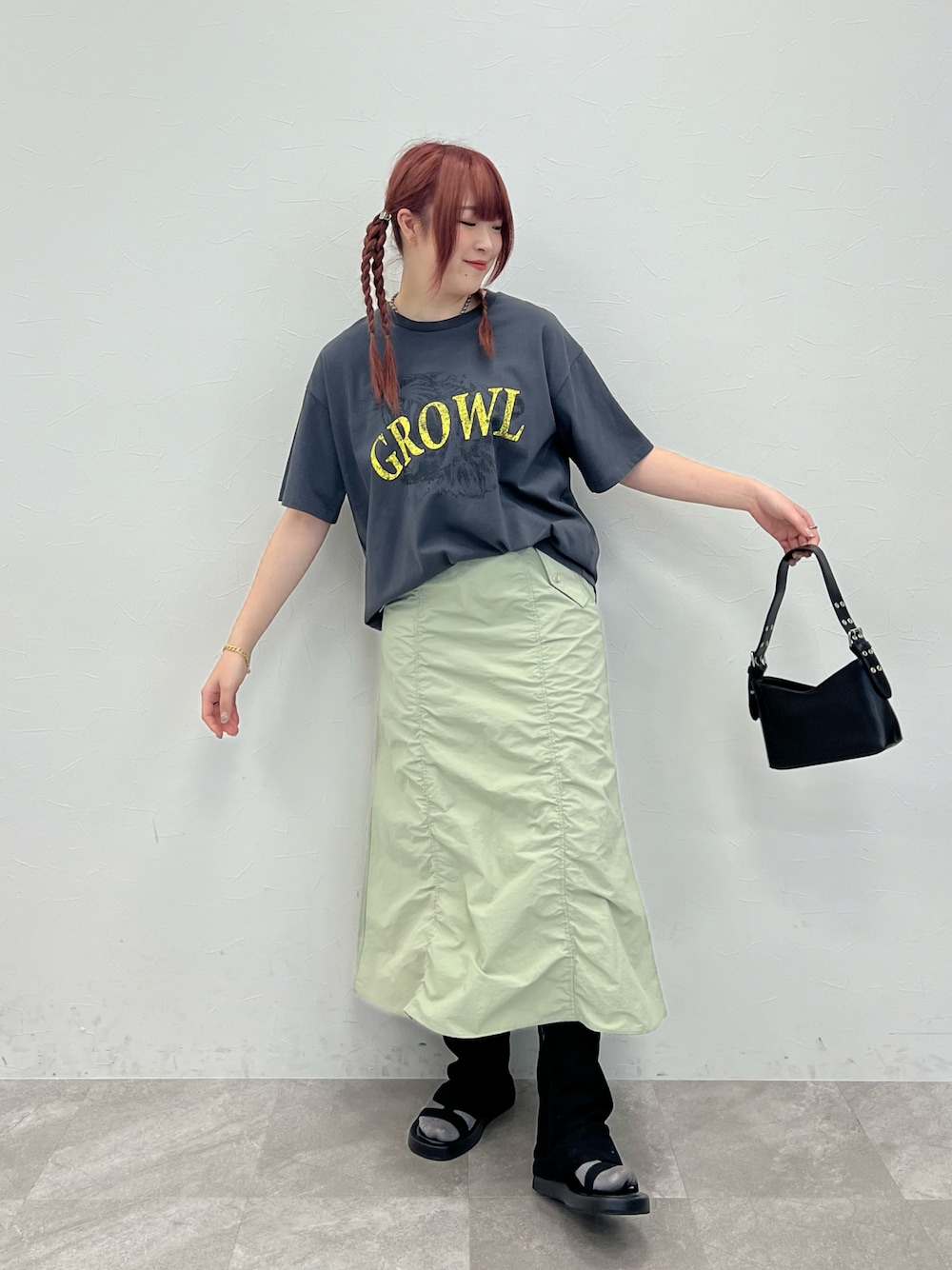 グレー系のTシャツ/カットソー、グリーン系のスカート、ブラック系のサンダルを着用したレディースの春コーディネートの1枚目の写真