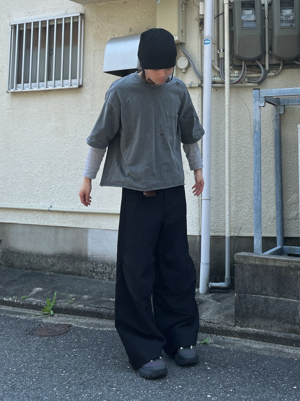 ブラック系のスラックス、グレー系のスニーカー、グリーン系のニットキャップ/ビーニーを着用したメンズの春コーディネートの1枚目の写真