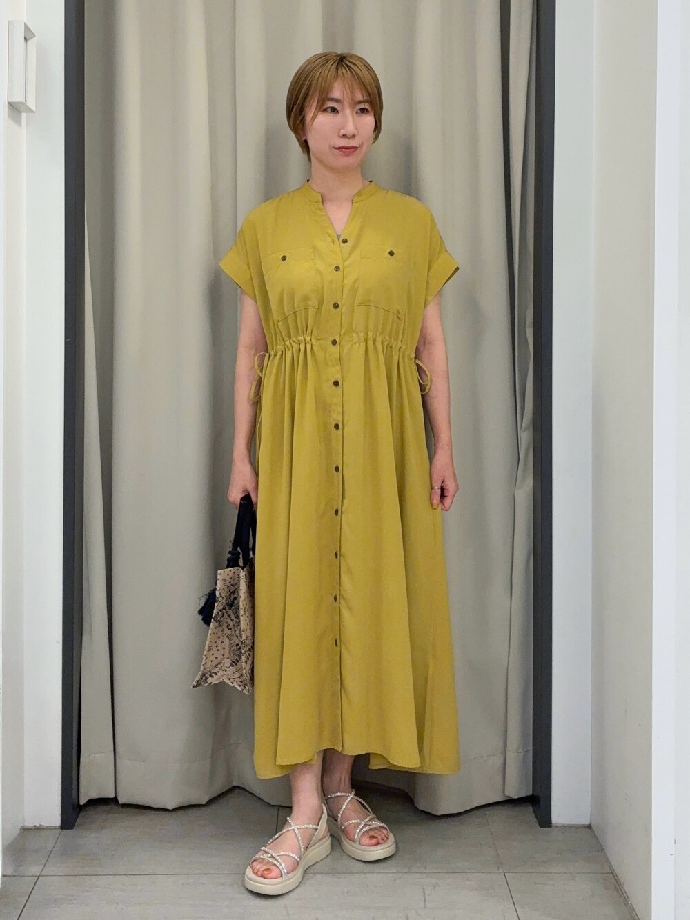 イエロー系のワンピース、ブルー系のトートバッグを着用したレディースの春コーディネートの1枚目の写真