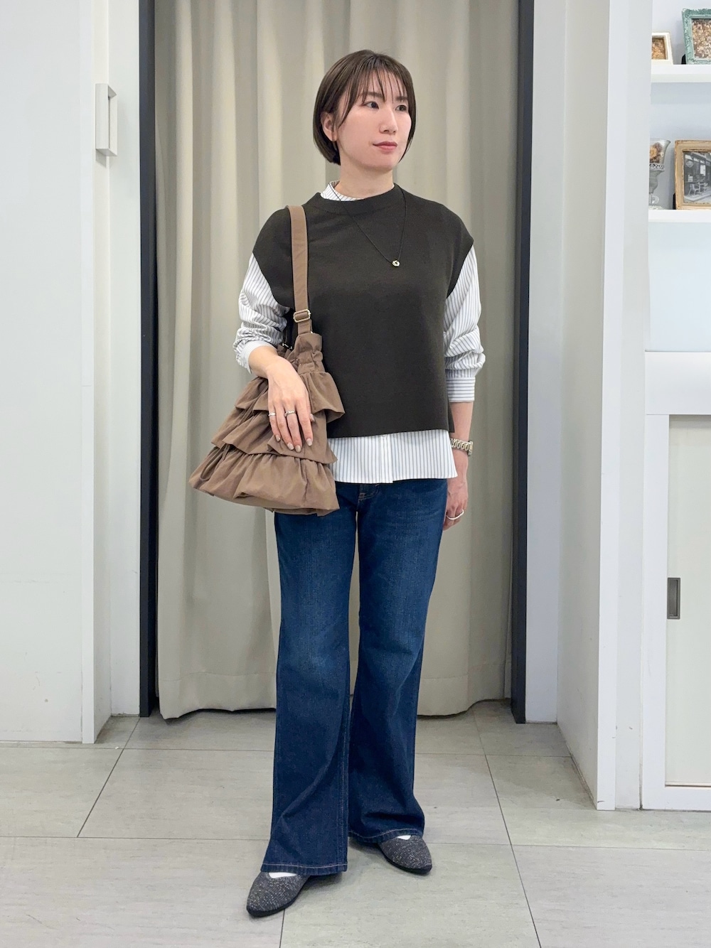 ブルー系のデニムパンツ、グレー系のパンプス、ゴールド系のネックレスを着用したレディースの秋コーディネートの1枚目の写真