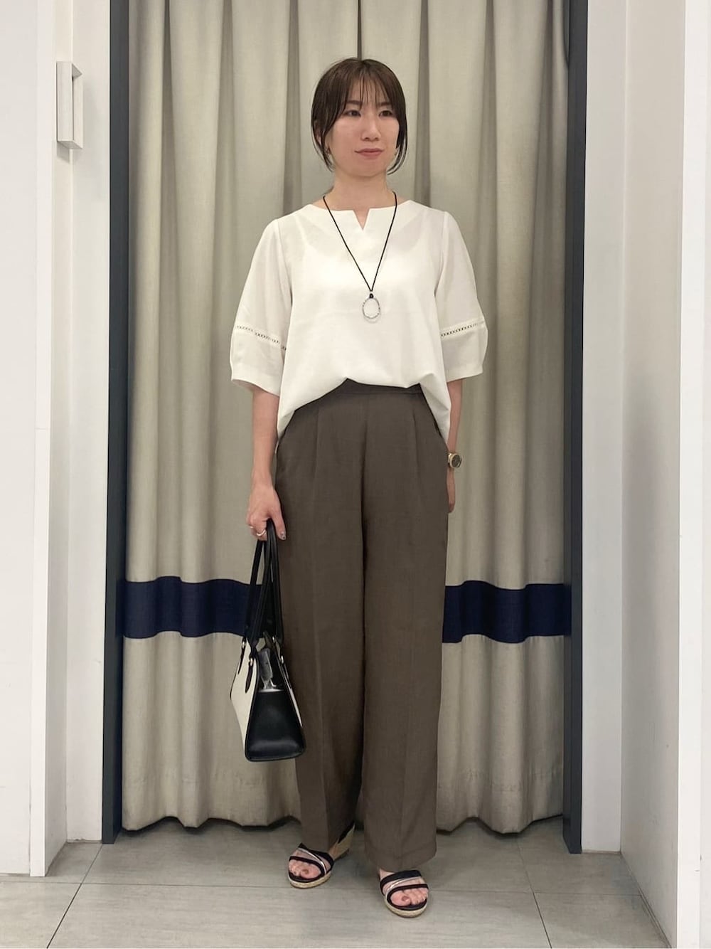 ホワイト系のシャツ/ブラウス、ブラウン系のその他パンツ、ブラック系のボストンバッグを着用したレディースの夏コーディネートの1枚目の写真