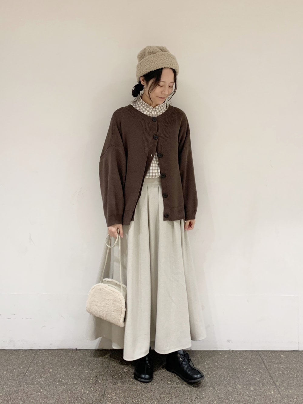 ブラウン系のニット/セーター、ベージュ系のシャツ/ブラウス、ベージュ系のスカートを着用したレディースの冬コーディネートの1枚目の写真