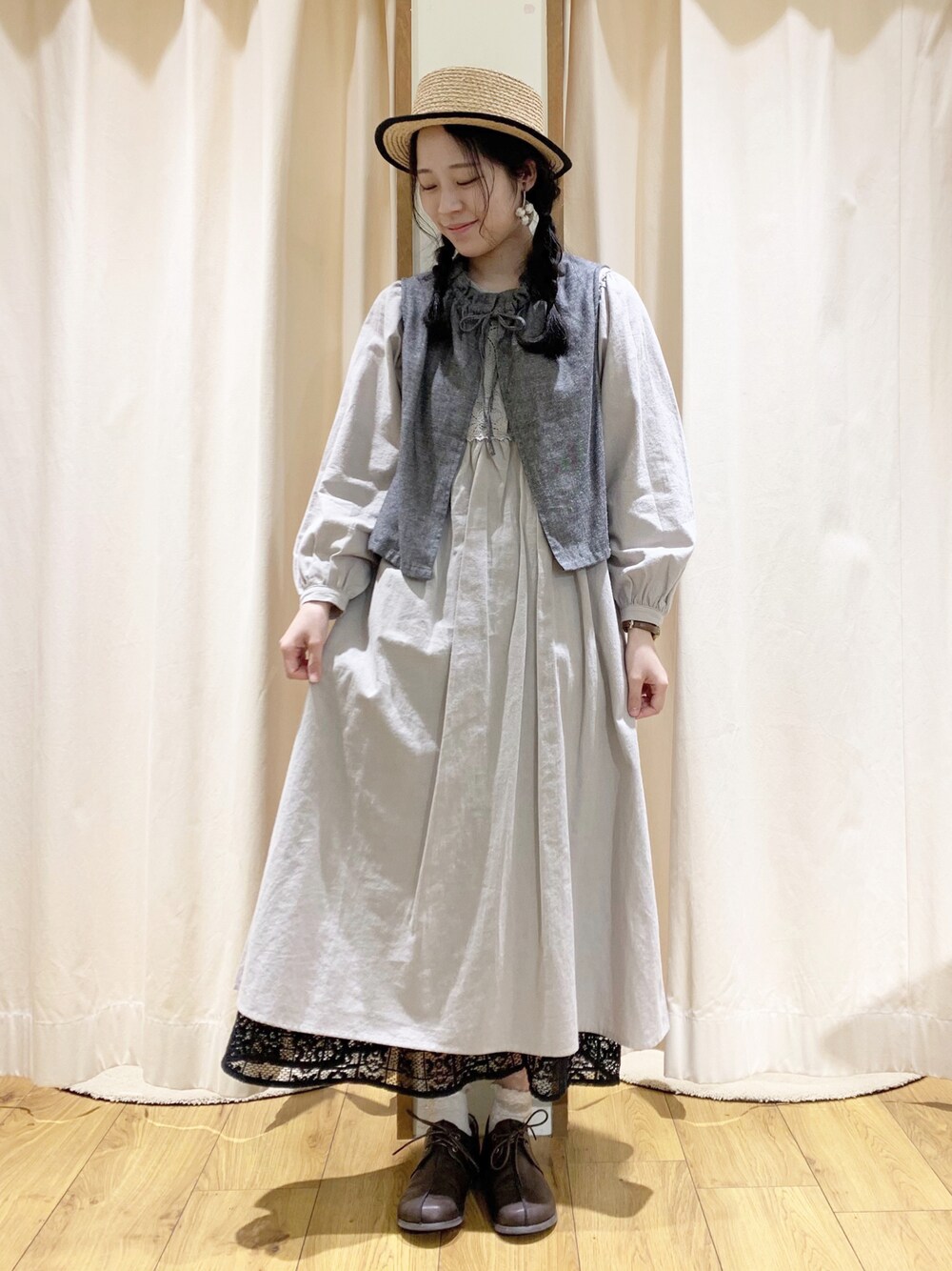 グレー系のベスト、グレー系のワンピース、ブラック系のスカートを着用したレディースの春コーディネートの1枚目の写真