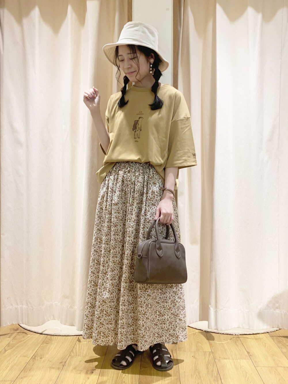 イエロー系のTシャツ/カットソー、オレンジ系のスカート、ホワイト系のTシャツ/カットソーを着用したレディースの春コーディネートの1枚目の写真