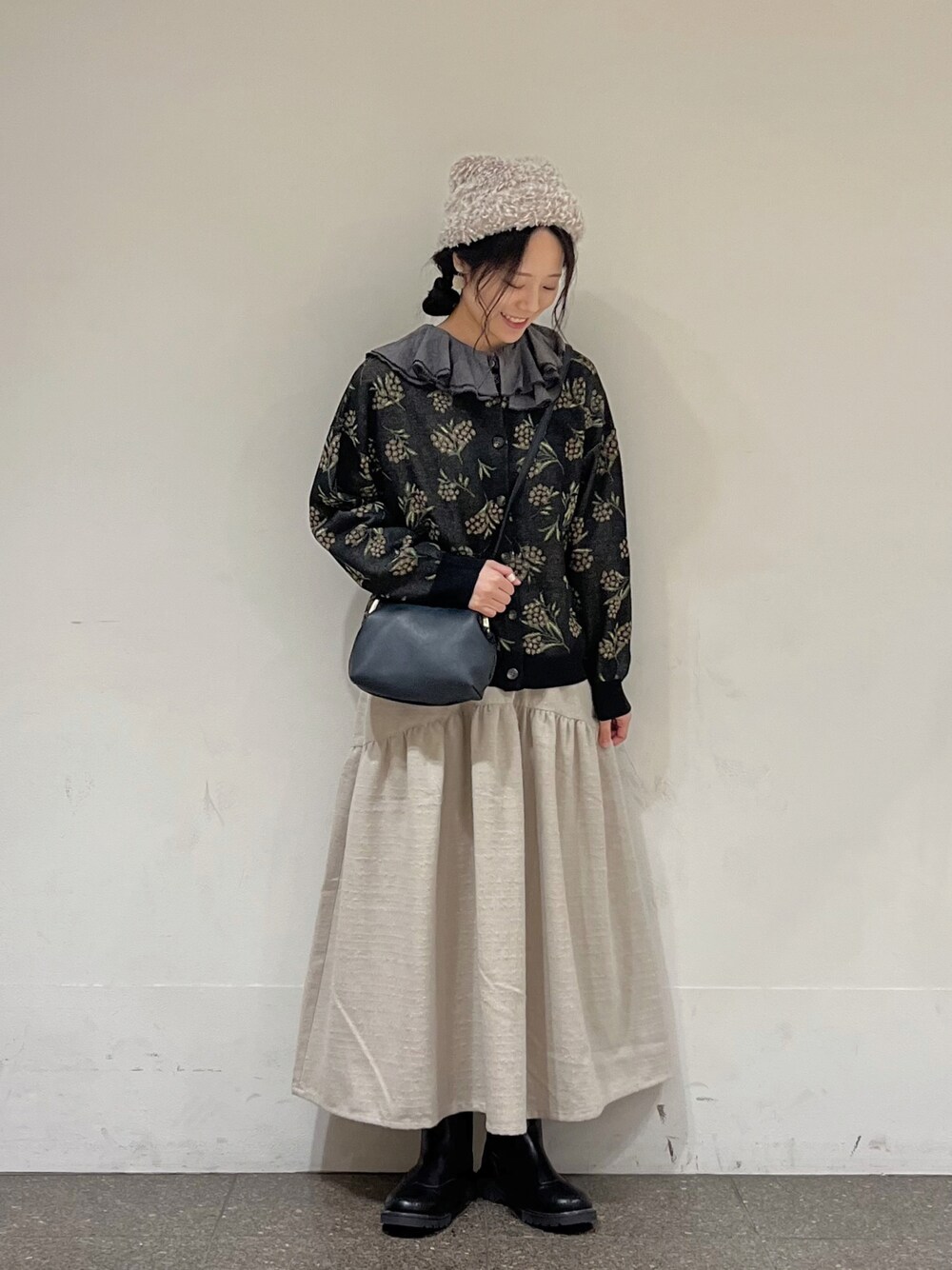 ブラック系のカーディガン/ボレロ、グレー系のシャツ/ブラウス、ホワイト系のスカートを着用したレディースの冬コーディネートの1枚目の写真