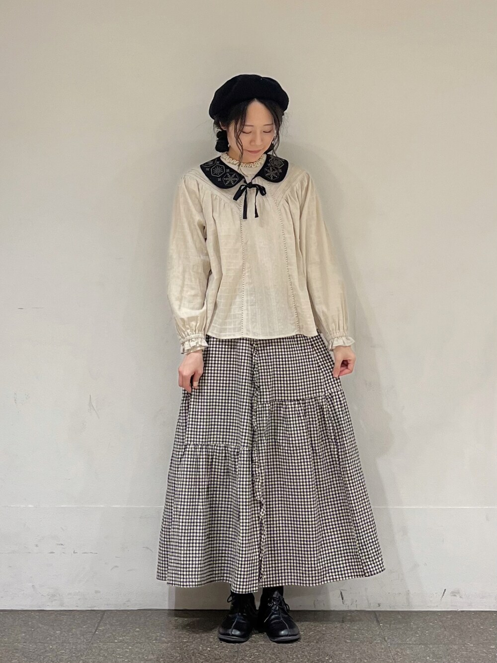 ベージュ系のシャツ/ブラウス、ブラック系のスカート、グレー系のカーディガン/ボレロを着用したレディースの冬コーディネートの1枚目の写真