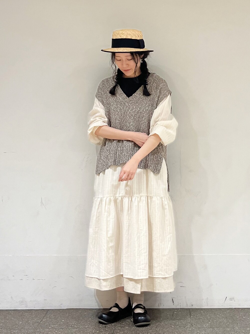 ブラウン系のベスト、ホワイト系のワンピース、ベージュ系のスカートを着用したレディースの冬コーディネートの1枚目の写真