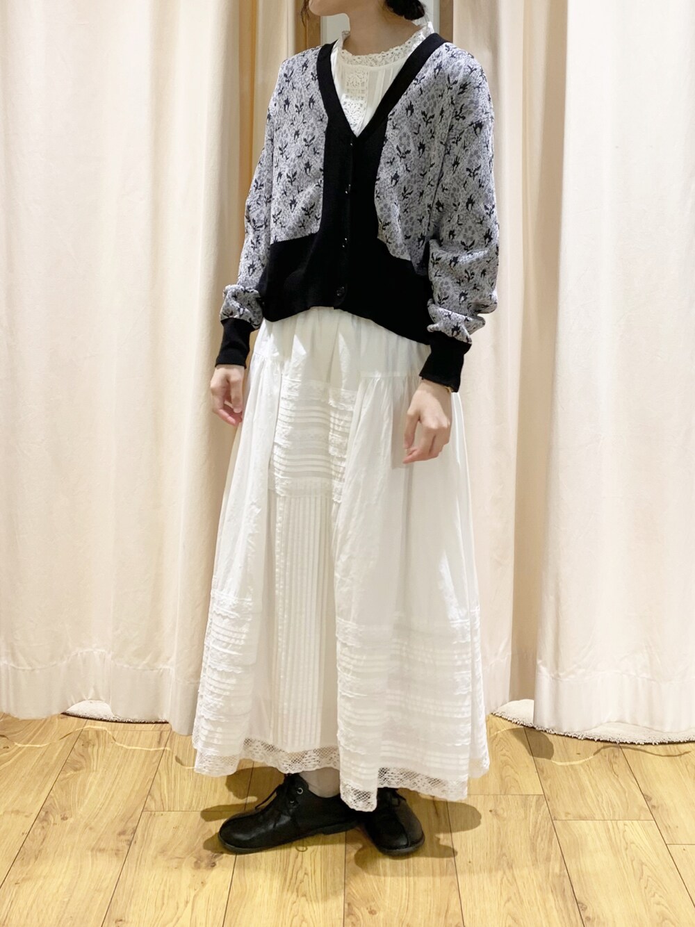ブラック系のカーディガン/ボレロ、ホワイト系のスカート、ホワイト系のタンクトップを着用したレディースの春コーディネートの1枚目の写真