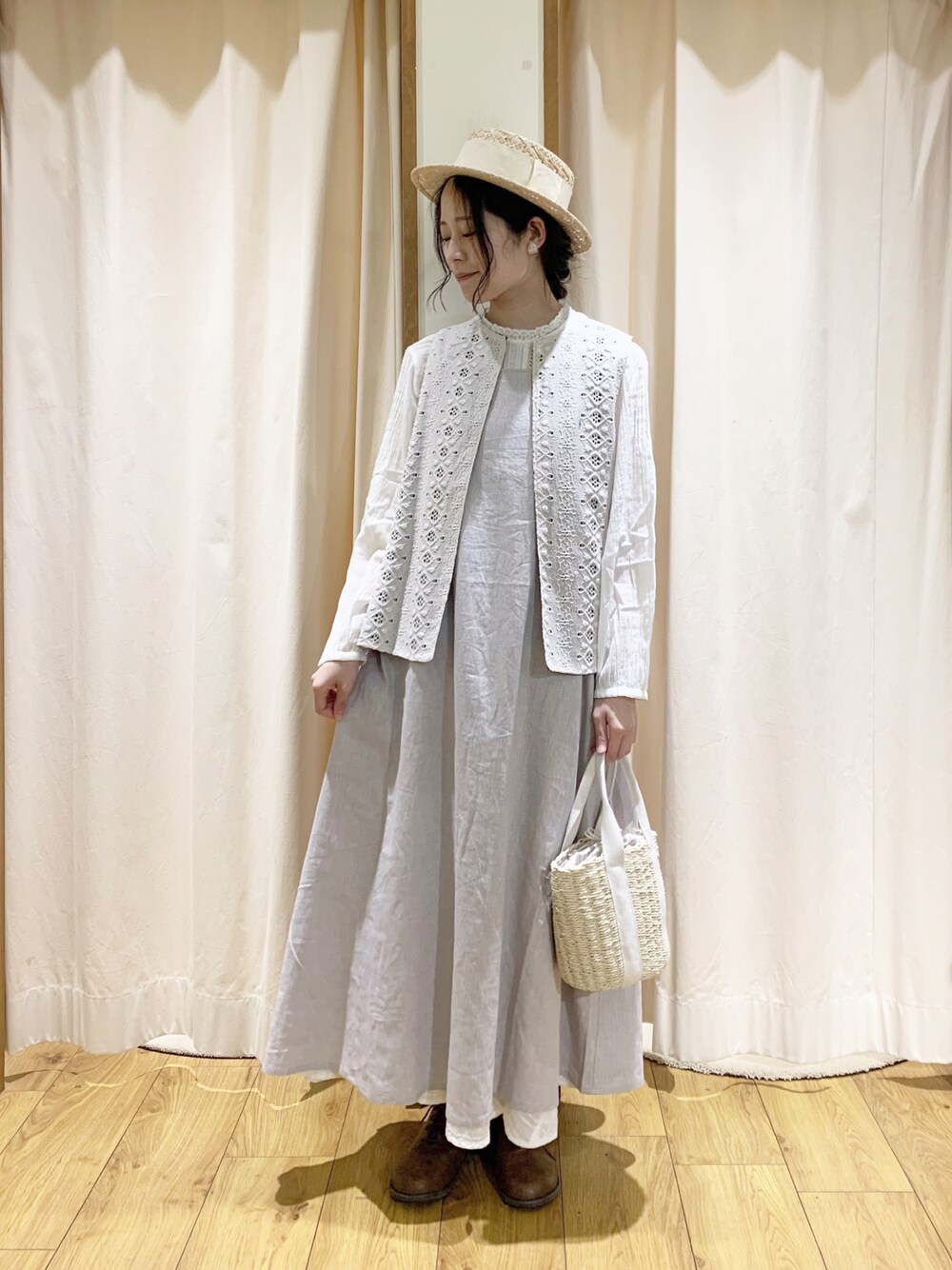 グレー系のワンピース、ホワイト系のベスト、ホワイト系のスカートを着用したレディースの春コーディネートの1枚目の写真