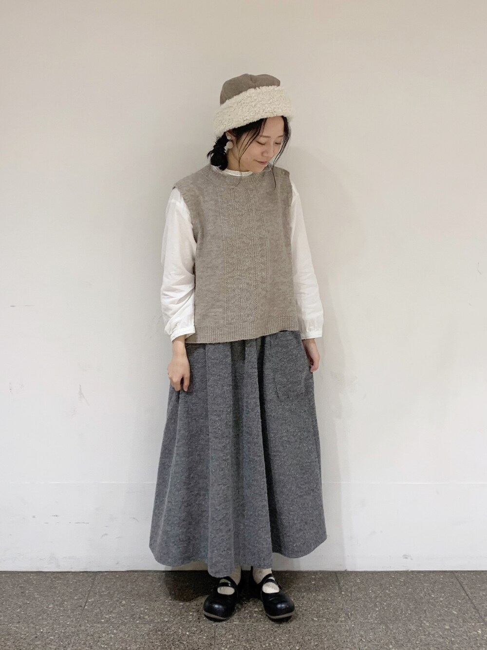 ベージュ系のベスト、ホワイト系のシャツ/ブラウス、ブラック系のスカートを着用したレディースの秋コーディネートの1枚目の写真