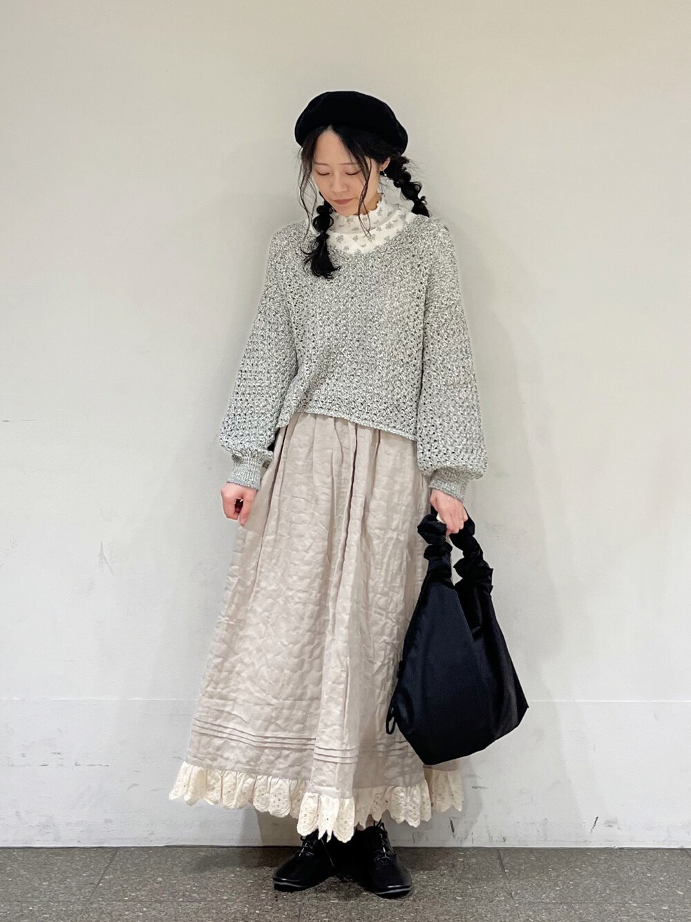 ブルー系のTシャツ/カットソー、ブラック系のカーディガン/ボレロ、ベージュ系のスカートを着用したレディースの冬コーディネートの1枚目の写真