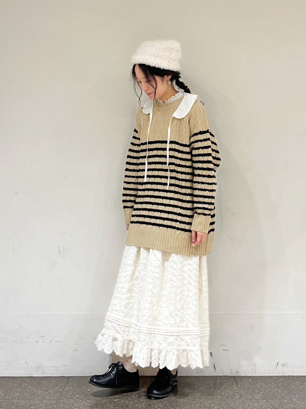 ベージュ系のニット/セーター、ホワイト系のシャツ/ブラウス、ホワイト系のスカートを着用したレディースの冬コーディネートの1枚目の写真