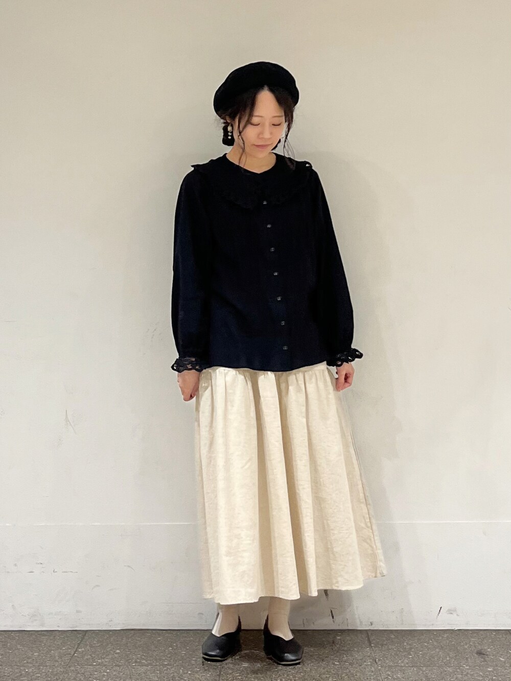 ブラック系のシャツ/ブラウス、ベージュ系のスカートを着用したレディースの冬コーディネートの1枚目の写真