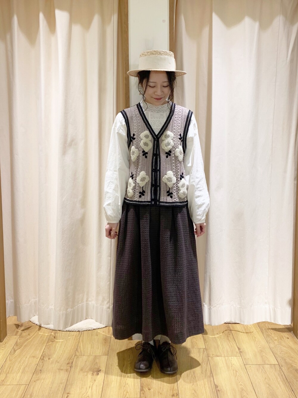 ベージュ系のベスト、ホワイト系のシャツ/ブラウス、グレー系のスカートを着用したレディースの春コーディネートの1枚目の写真
