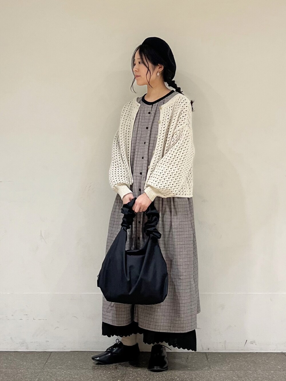 ブラック系のワンピース、ベージュ系のカーディガン/ボレロ、ブラック系のスカートを着用したレディースの冬コーディネートの1枚目の写真