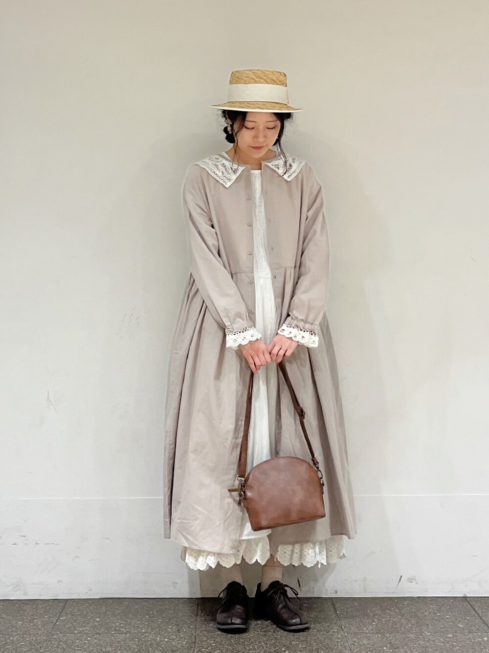 ホワイト系のワンピース、ホワイト系のスカート、ブラウン系のハンドバッグを着用したレディースの冬コーディネートの1枚目の写真