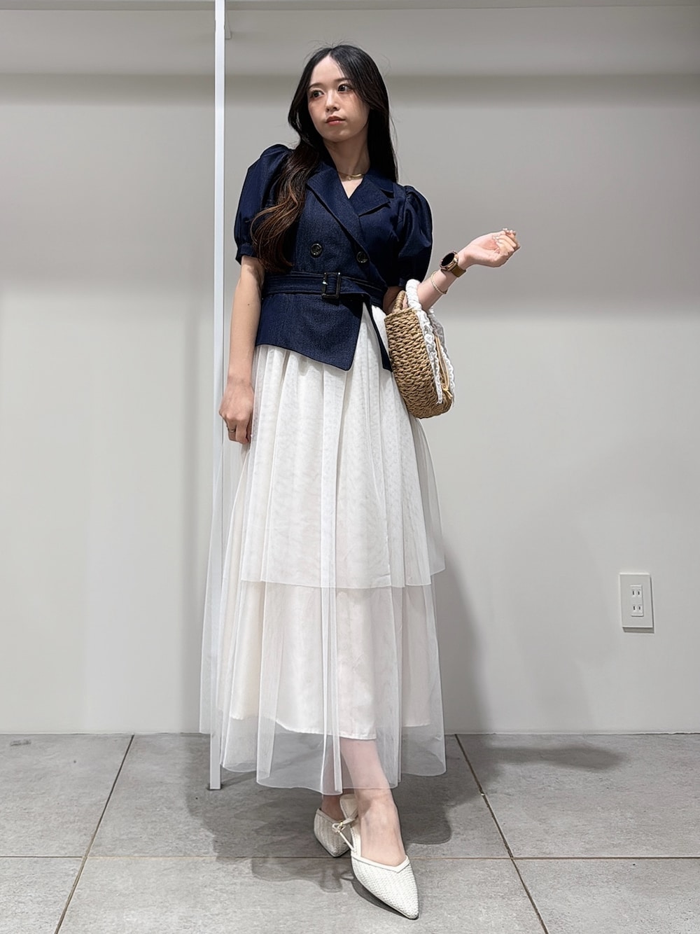 ベージュ系のハンドバッグ、ブルー系のワンピース、ホワイト系のパンプスを着用したレディースの春コーディネートの1枚目の写真