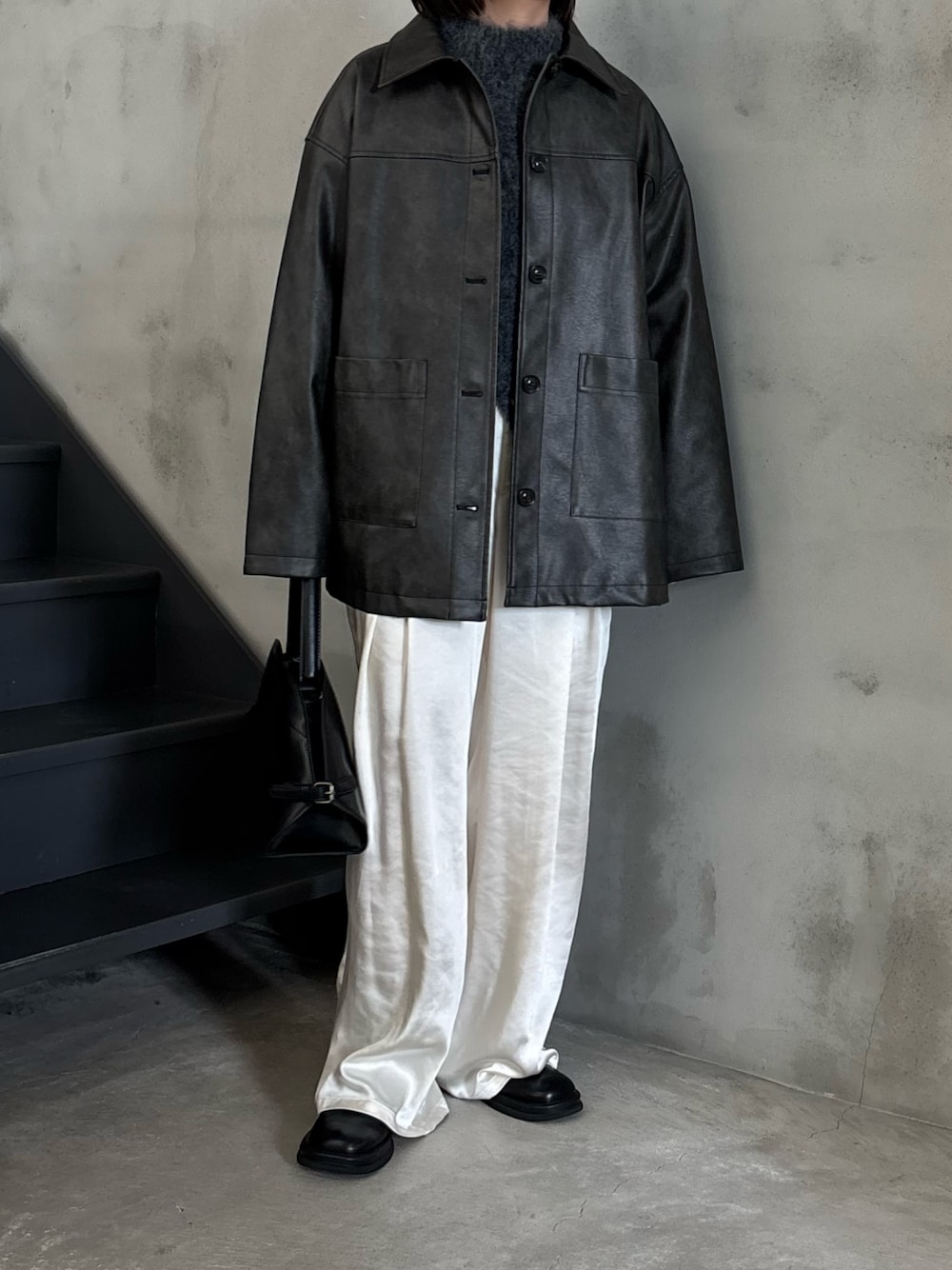 ブラック系のステンカラーコート、グレー系のニット/セーター、ブラック系のスリッポンを着用したレディースの秋コーディネートの1枚目の写真