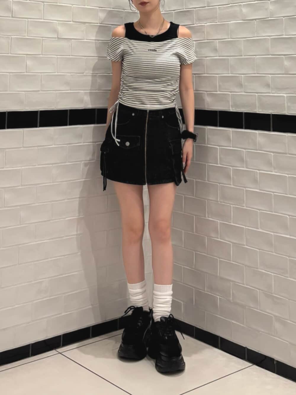 ブラック系のスニーカー、ブラック系のスカート、ホワイト系のTシャツ/カットソーを着用したレディースの夏コーディネートの1枚目の写真